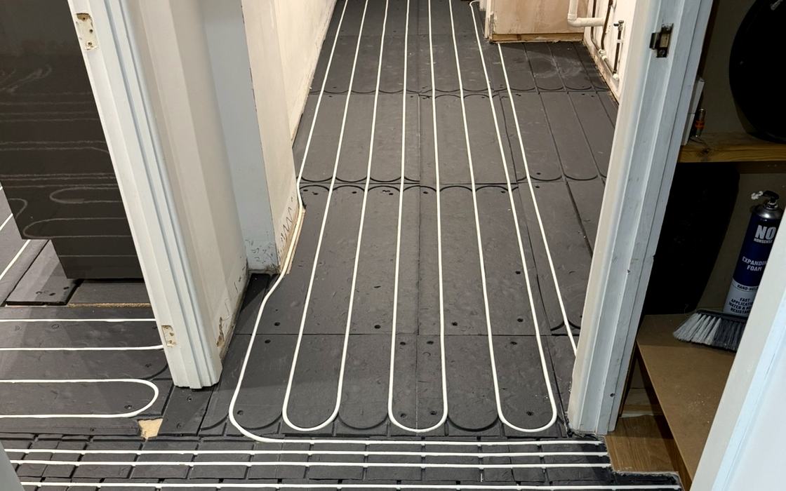 Underfloor heating pipe loops laid across a hallway